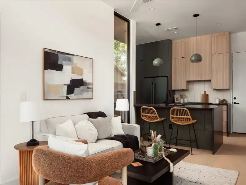 An open-concept design connects the living area to a modern kitchen with sophisticated cabinetry and pendant lighting. An open-concept design connects the living area to a modern kitchen with sophisticated cabinetry and pendant lighting.