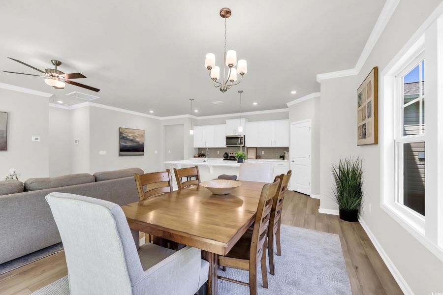 Dining space featuring ornamental molding, light wood finished floors, a chandelier, recessed lighting, and ceiling fan