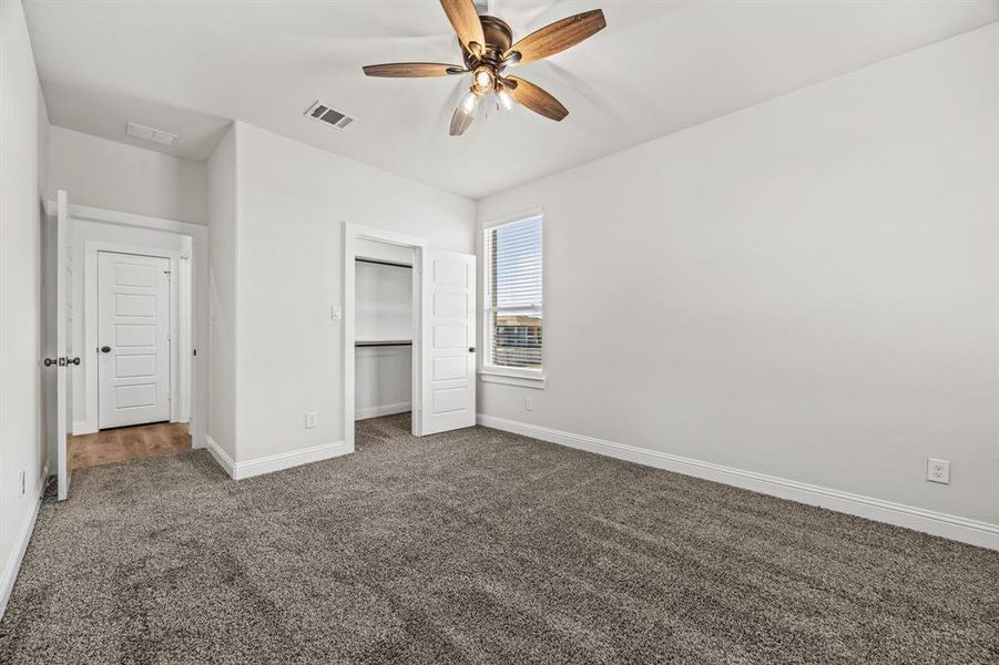 Unfurnished bedroom with ceiling fan, a closet, and dark carpet