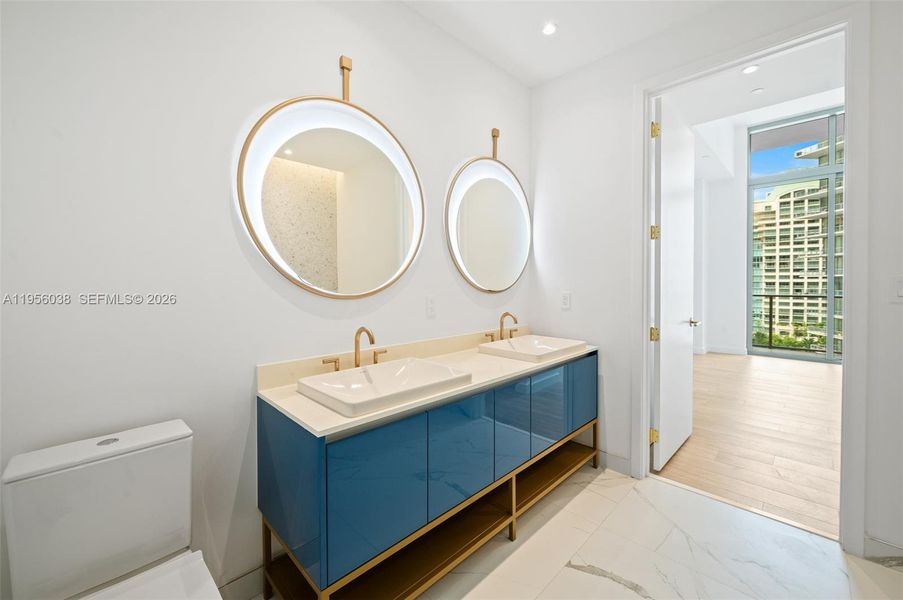 Spa-inspired bathroom featuring sleek modern vanity, quartz countertop, designer fixtures, and glass-enclosed shower with elegant tile finishes at Mr. C Residences Coconut Grove.