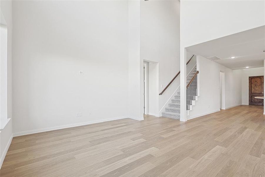 Unfurnished living room with light hardwood / wood-style flooring and a towering ceiling