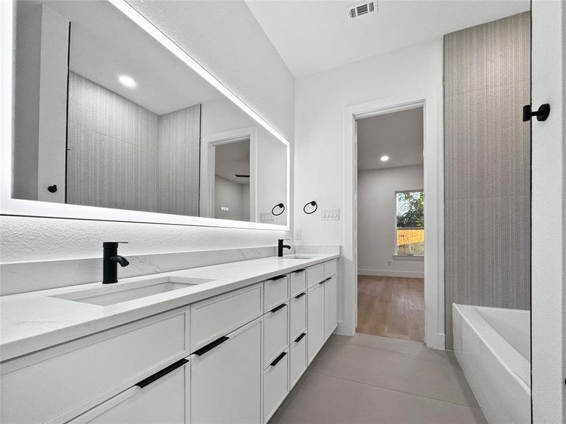 Bathroom with double vanity, a tub, light tile patterned floors, and recessed lighting