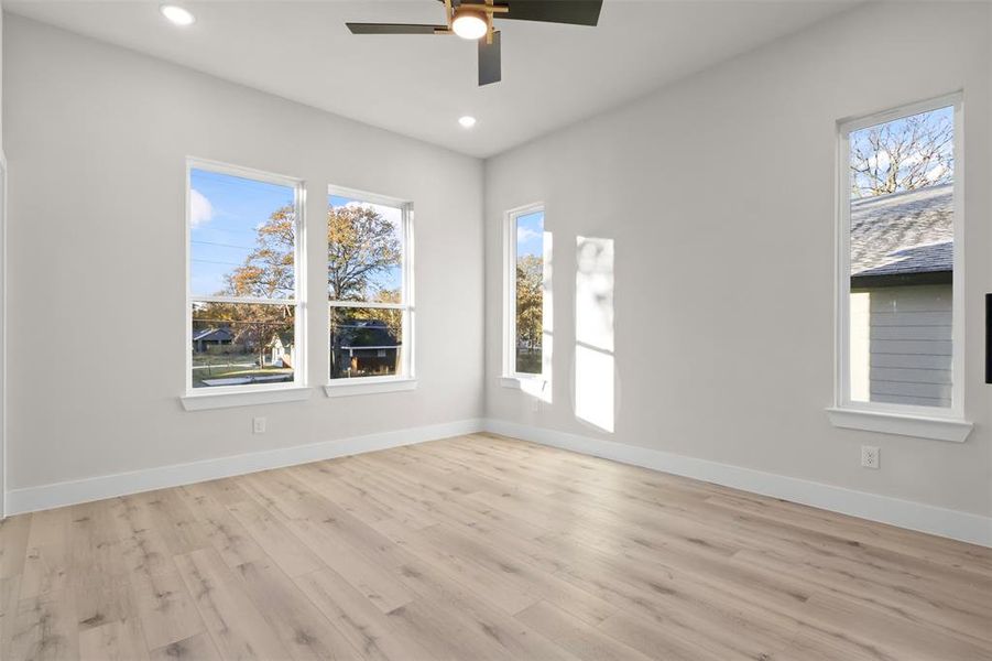 Empty room featuring a wealth of natural light, light hardwood / wood-style flooring, and ceiling fan