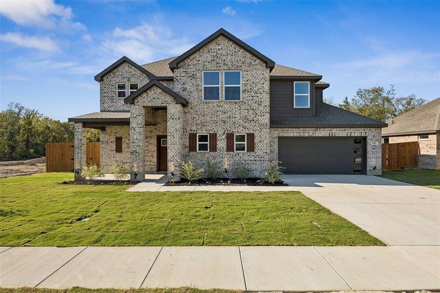 View of front facade featuring brick siding, a garage, concrete driveway, and roof with shingles