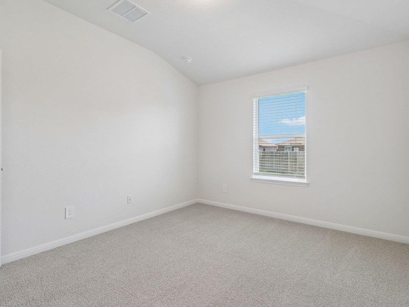 A vaulted ceiling and soft carpeting enhance this peaceful bedroom space.
