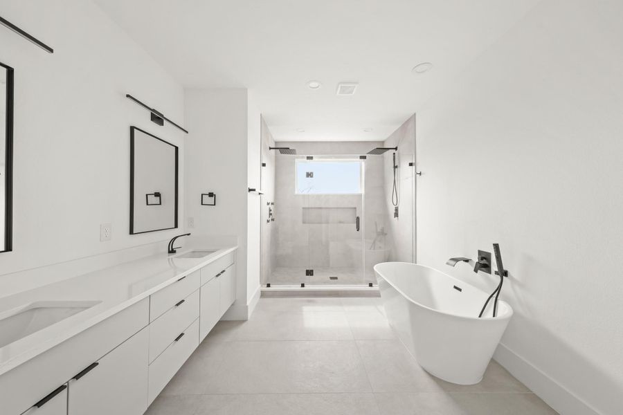 Beautifully appointed, the owner's private bath includes inset floating cabinetry supporting a Quartz countertop, dual under mount sinks, large black-framed mirrors with lighting above and large tile floors. Beautifully appointed, the owner's private bath includes inset floating cabinetry supporting a Quartz countertop, dual under mount sinks, large black-framed mirrors with lighting above and large tile floors.