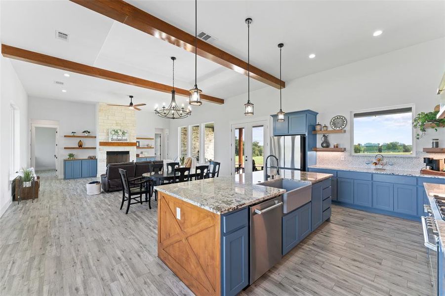 Expansive kitchen and living area featuring a large center island with a farmhouse sink, stainless steel appliances, and blue cabinetry