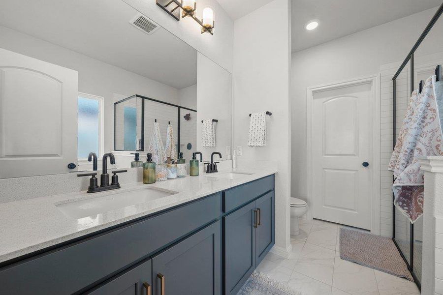 Bathroom featuring a shower stall, double vanity, light marble finish flooring, and recessed lighting