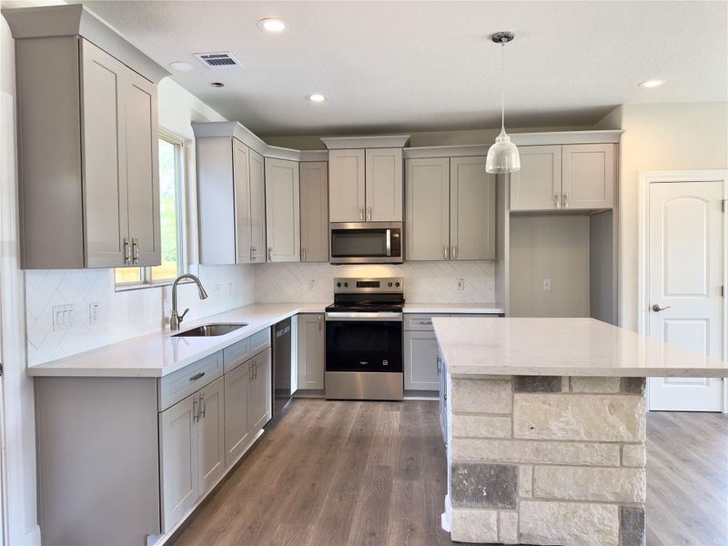 Kitchen with stainless steel appliances, gray cabinetry, Luxury Vinyl Plank floors, and recessed lighting Kitchen with stainless steel appliances, gray cabinetry, Luxury Vinyl Plank floors, and recessed lighting