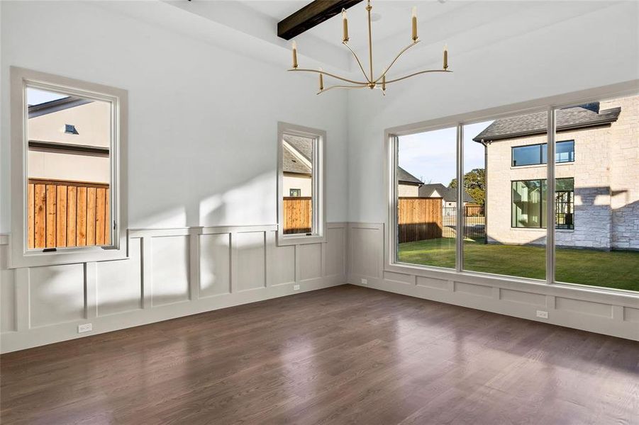 Bonus room featuring dark wood-style flooring, a wainscoted wall, a decorative wall, and a chandelier Bonus room featuring dark wood-style flooring, a wainscoted wall, a decorative wall, and a chandelier