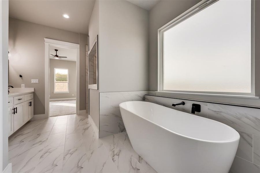 Bathroom featuring a bath, tile walls, tile patterned flooring, and vanity