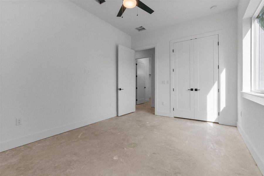 Unfurnished bedroom with concrete floors, a ceiling fan, and a closet Unfurnished bedroom with concrete floors, a ceiling fan, and a closet