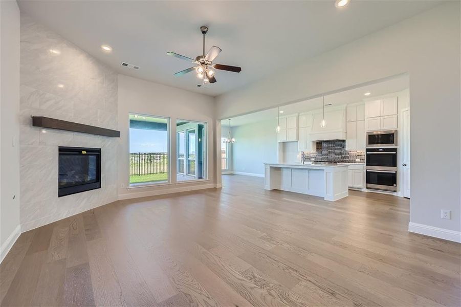 Unfurnished living room with a high end fireplace, ceiling fan, and light hardwood / wood-style floors