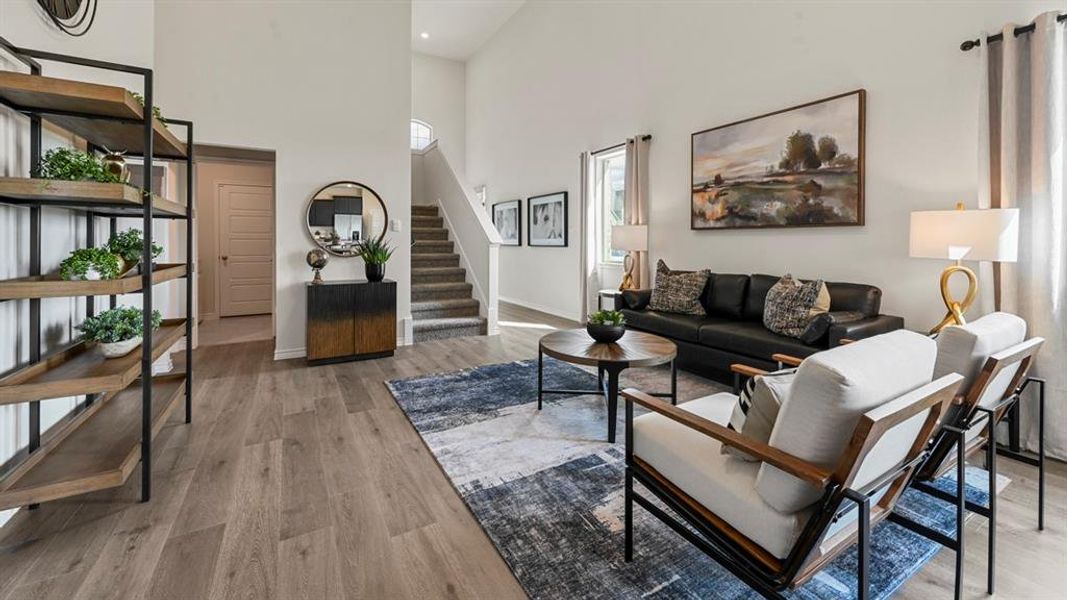 Living room with light wood-type flooring, a towering ceiling, and stairs Living room with light wood-type flooring, a towering ceiling, and stairs