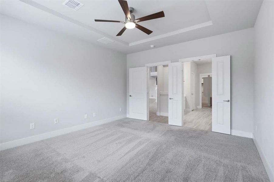 First-floor primary bedroom with a tray ceiling, flooded with natural light and offering plenty of space