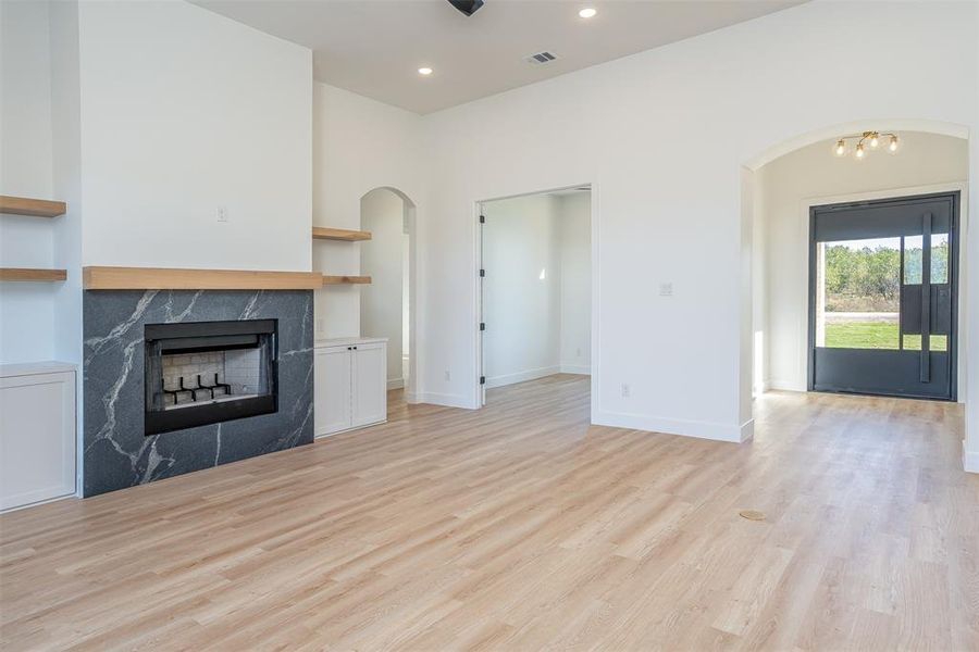 Unfurnished living room with a premium fireplace, light hardwood / wood-style flooring, and a notable chandelier