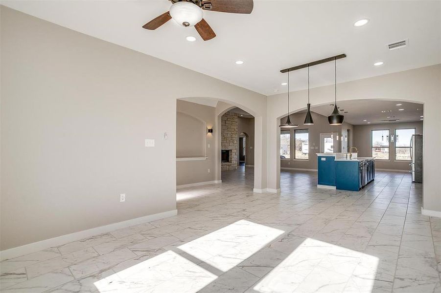 Unfurnished room with a large fireplace, ceiling fan, french doors, and sink