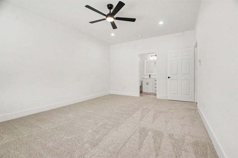 This room features neutral-toned carpet, white walls, and a black ceiling fan with integrated lighting