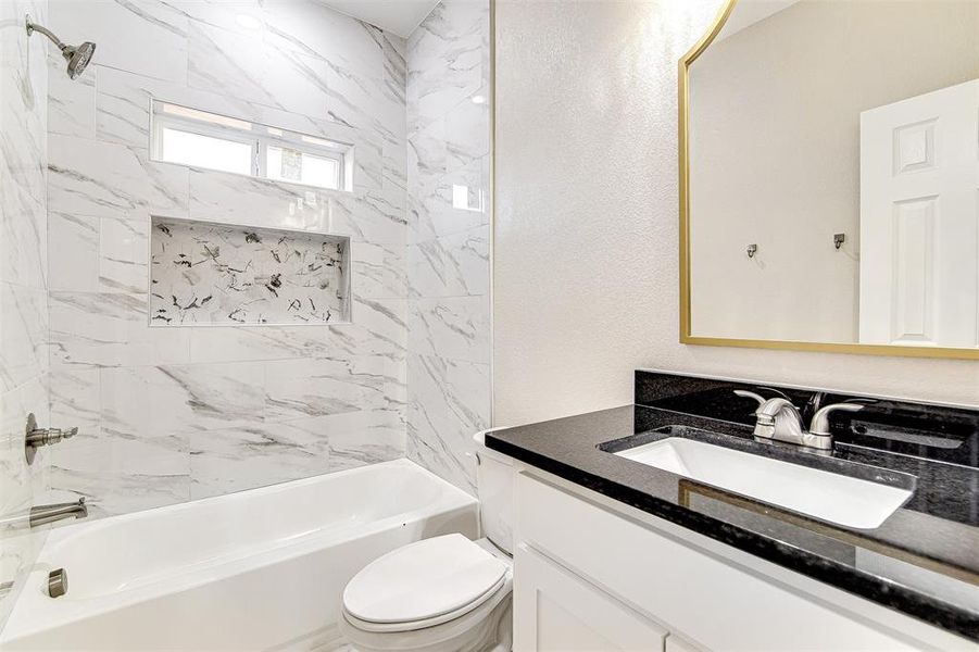 Full bathroom with tiled shower / bath combo, toilet, and vanity