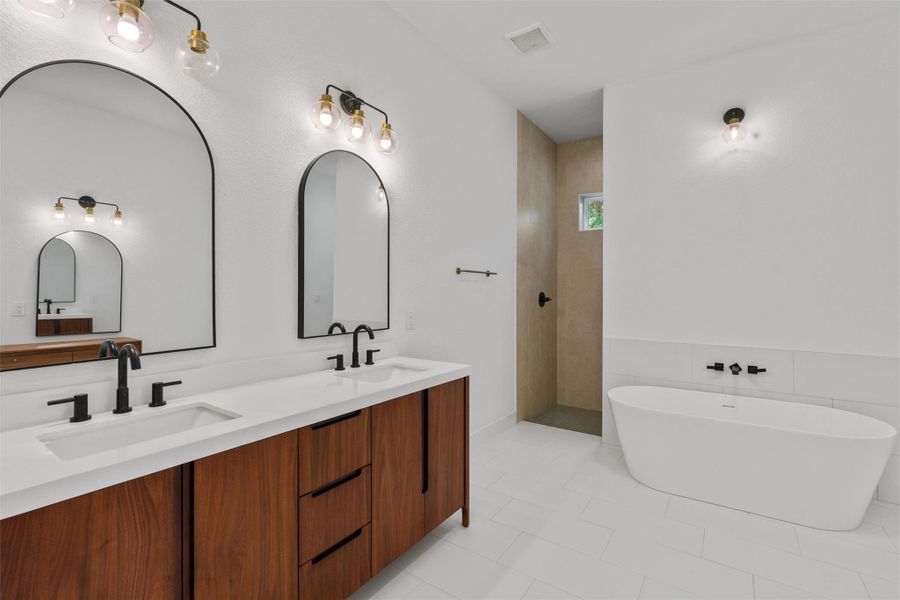 A well-lit primary bathroom featuring a freestanding tub and a spacious dual vanity.