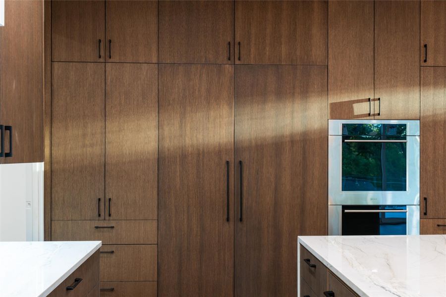 Kitchen featuring stainless steel double oven, light stone counters, and modern cabinets