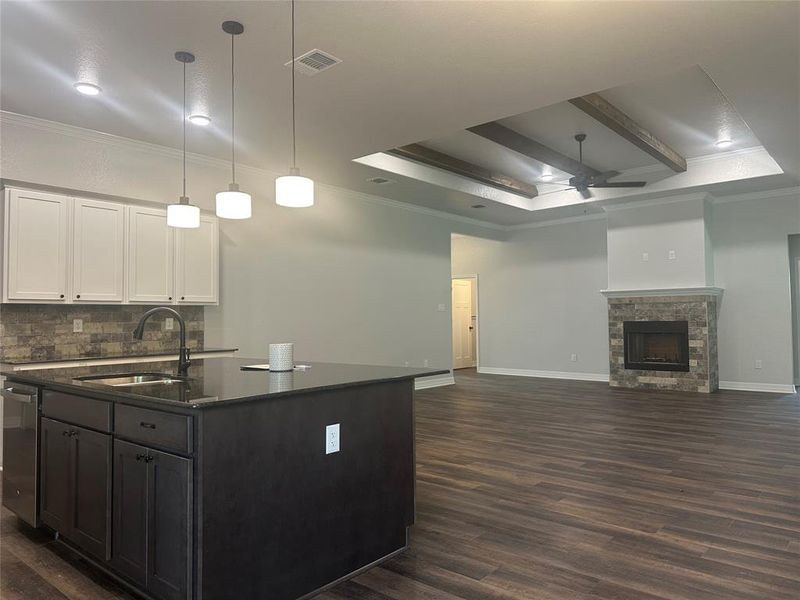 Kitchen with a ceiling fan, dark wood finished floors, backsplash, a raised ceiling, and white cabinetry