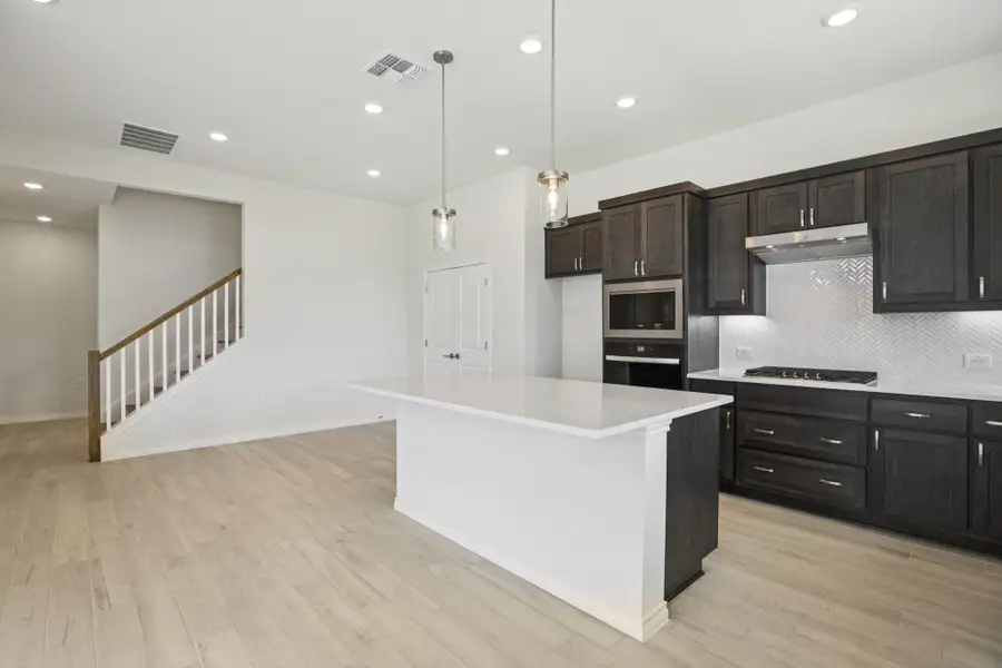 Kitchen featuring recessed lighting, decorative backsplash, light wood finished floors, a kitchen island, and hanging light fixtures