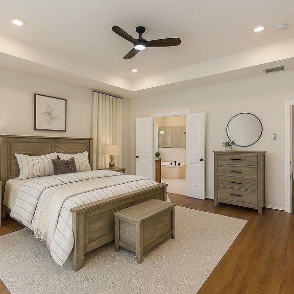 This bedroom is spacious and inviting, featuring a modern ceiling fan, wood flooring, and warm, neutral tones. It includes a large bed, matching wooden furniture, and an ensuite bathroom with double doors. The decor is minimal, with a framed artwork and a round mirror enhancing the cozy atmosphere. Staged to help buyers visualize.