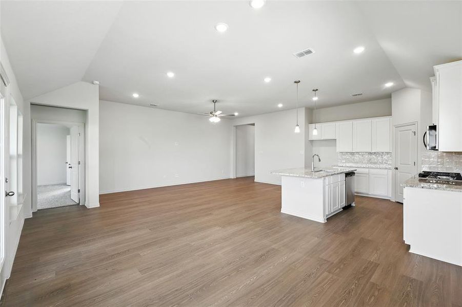 Kitchen featuring backsplash, a kitchen island with sink, light stone counters, light wood finished floors, and recessed lighting Kitchen featuring backsplash, a kitchen island with sink, light stone counters, light wood finished floors, and recessed lighting
