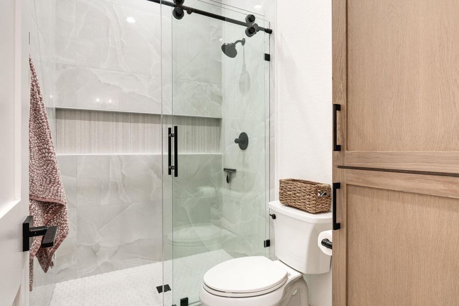 Full bathroom with toilet and a marble finish shower