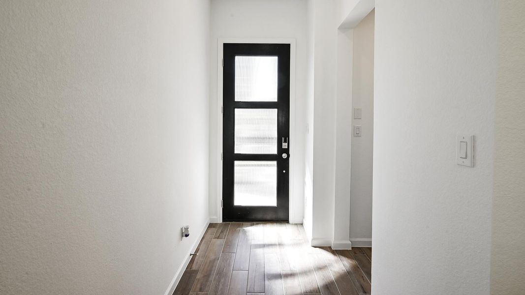 Doorway to outside featuring dark wood-type flooring and a textured wall Doorway to outside featuring dark wood-type flooring and a textured wall