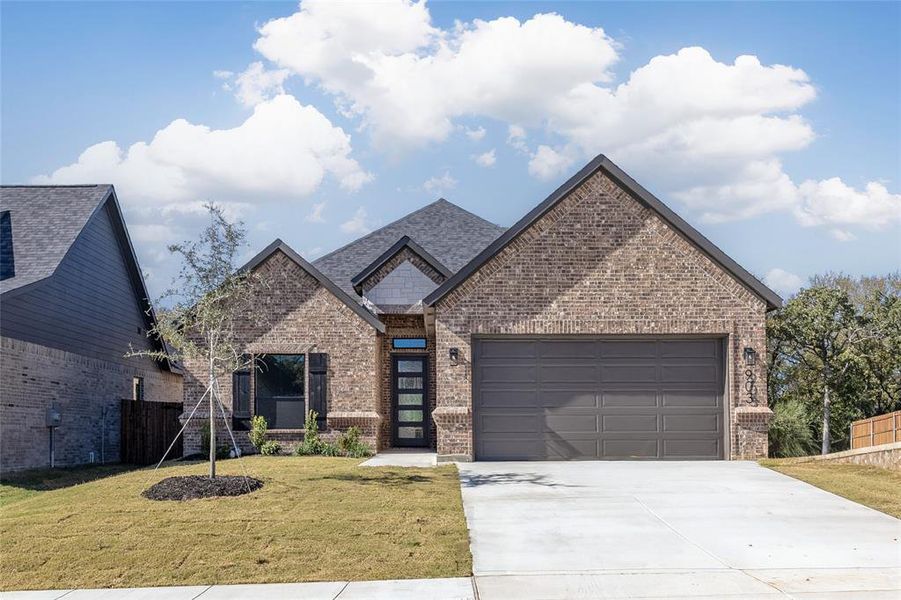 View of front of home featuring brick siding, concrete driveway, and an attached garage