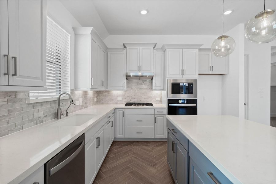 The kitchen features elegant cabinetry, pristine quartz countertops, window over the kitchen sink, and a large kitchen island that doubles as a functional breakfast bar. The kitchen features elegant cabinetry, pristine quartz countertops, window over the kitchen sink, and a large kitchen island that doubles as a functional breakfast bar.