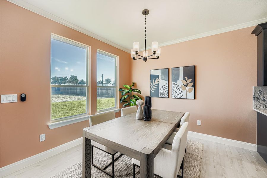 Dining space featuring ornamental molding, a chandelier, and light wood-style floors