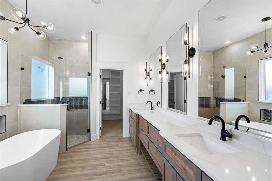 Bathroom with shower with separate bathtub, vanity, and an inviting chandelier