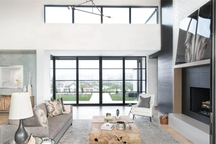 Living area featuring healthy amount of natural light, a fireplace, wood finished floors, and a high ceiling
