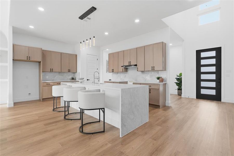 Kitchen featuring a breakfast bar area, light wood finish cabinets, light stone counters, and light wood-style floors