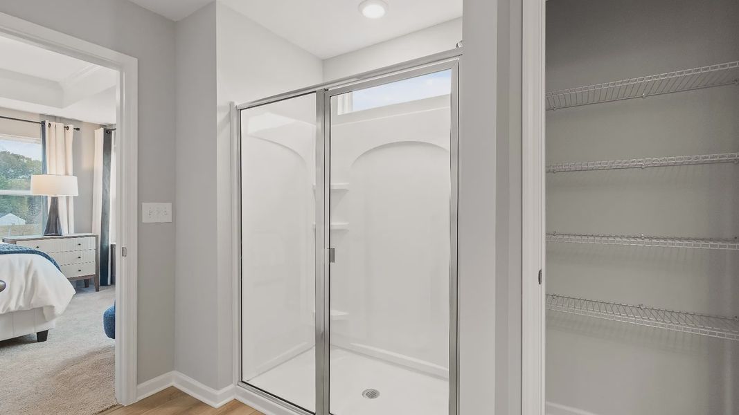 Modern bathroom featuring walk-in shower with glass door and sleek finishes in new construction townhome in Riverdale, GA.