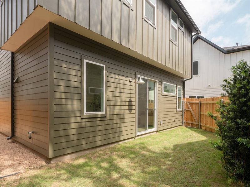 Exterior featuring horizontal olive green siding with vertical paneling on upper level, white frame windows, and a sliding glass door