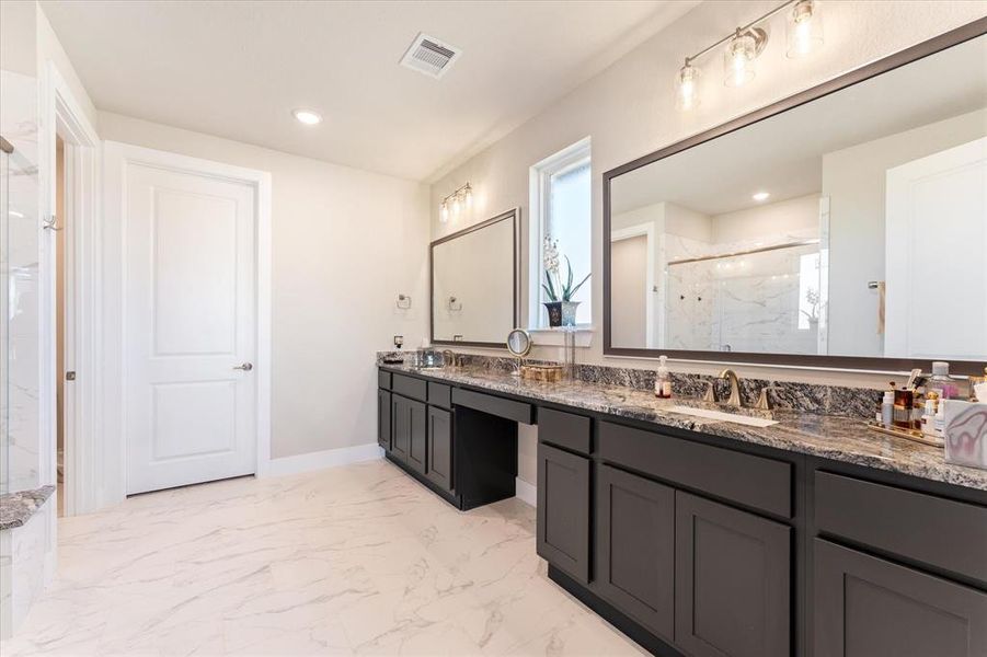 Primary bathroom with double sinks, large vanity and walk-in closet