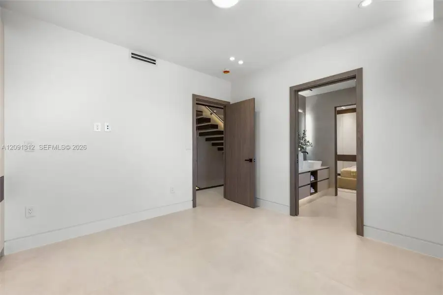 Interior space featuring neutral large-format tile flooring, recessed ceiling lighting, and wood-finish door frames Interior space featuring neutral large-format tile flooring, recessed ceiling lighting, and wood-finish door frames