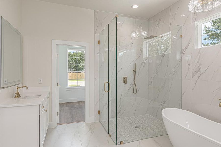 Spacious bathroom featuring a frameless glass shower enclosure, a freestanding soaking tub, and a white vanity with a rectangular sink