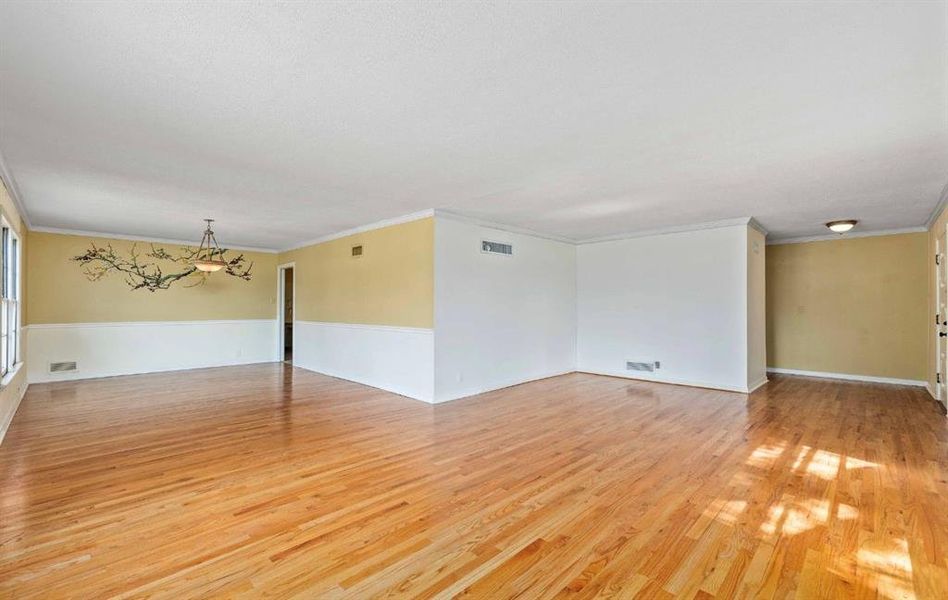 Unfurnished room with light wood-style flooring, a chandelier, and ornamental molding