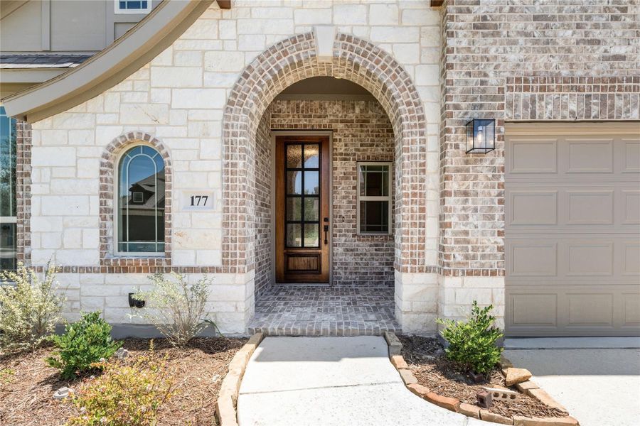 Home entrance with brick arched entryway, wood front door, and stone exterior at number 177 Home entrance with brick arched entryway, wood front door, and stone exterior at number 177