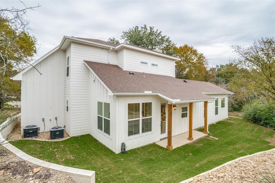 Back of property featuring a lawn, central air condition unit, and a patio