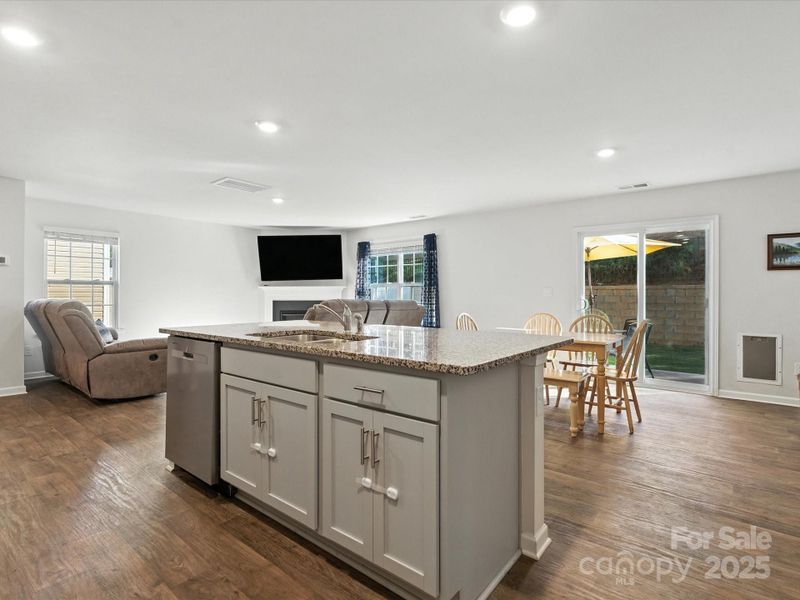 Stunning open-concept living featuring large kitchen island with granite countertops and bar seating. Seamless flow between kitchen, dining, and living areas perfect for entertaining and family gatherings.