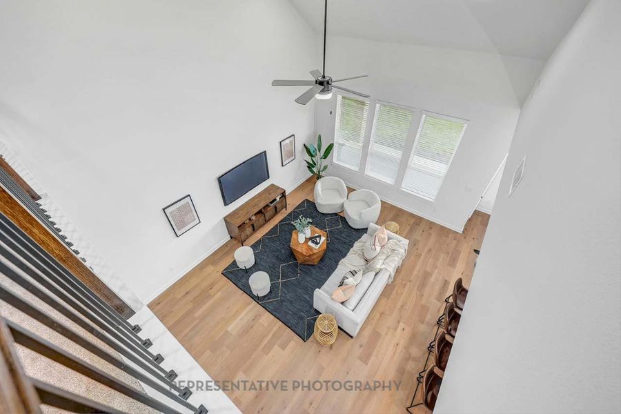 Living room featuring wood finished floors, high vaulted ceiling, and a ceiling fan Living room featuring wood finished floors, high vaulted ceiling, and a ceiling fan