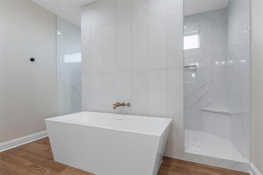 Full bath featuring a freestanding tub, wood finished floors, a marble finish shower, and tile walls Full bath featuring a freestanding tub, wood finished floors, a marble finish shower, and tile walls