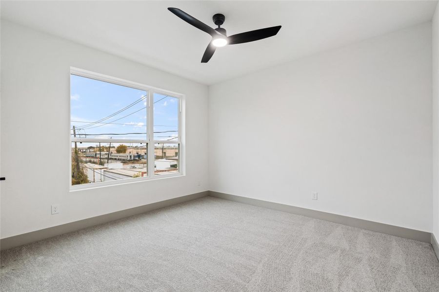 Bright and spacious, this secondary bedroom offers plush carpet, modern trim, and an oversized window that frames neighborhood views and floods the room with natural light—perfect as a guest suite, nursery, or creative flex space.