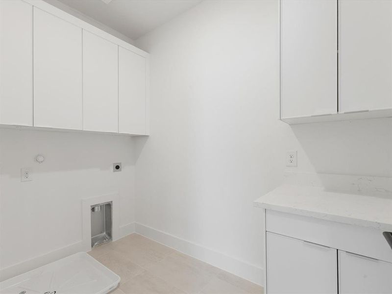 Laundry room with cabinets and folding space, hookup for an electric dryer, light tile patterned flooring, and gas dryer hookup